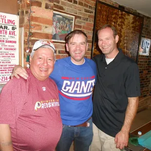 three men standing next to a pool table