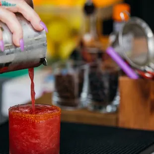 a person pouring a drink into a glass