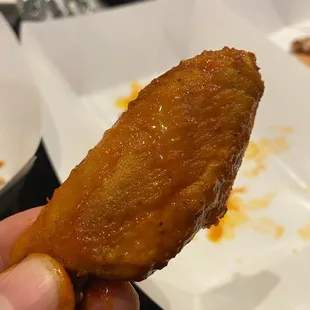 a hand holding a piece of fried chicken