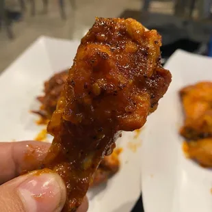 a hand holding a piece of chicken wings