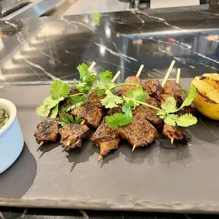 skewered steaks with a side of salsa