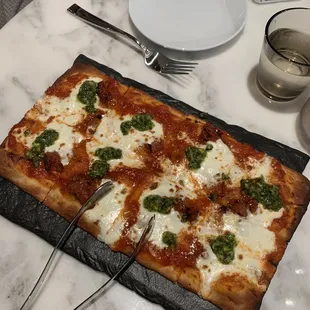 a square pizza with cheese and spinach