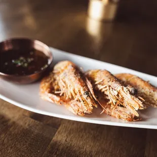 a plate of grilled shrimp with dipping sauce