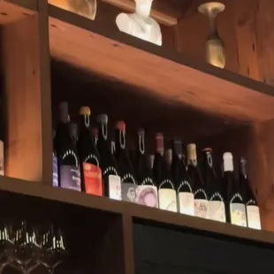 a shelf of wine bottles and wine glasses