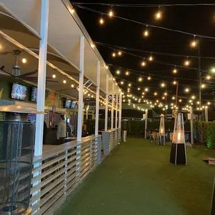 a patio area with lights strung from the ceiling