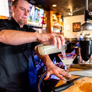 a bartender pouring a drink at a bar