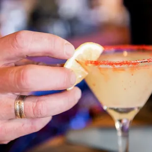 a person holding a cocktail glass with a slice of lemon