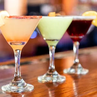 three cocktail glasses on a bar