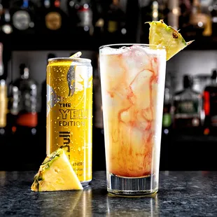 a tall glass with a pineapple garnish next to a tall glass with a pineapple garnish