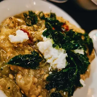 a bowl of soup with cheese and greens