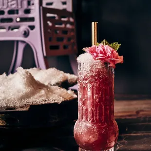 a pink drink with a straw and a flower garnish