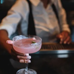 a bartender holding a pink drink