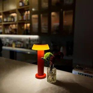 a table with a vase of flowers and a lamp