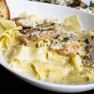 a bowl of pasta with chicken and parmesan bread