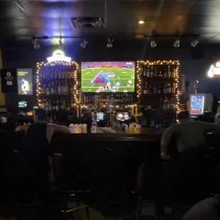 people sitting at the bar watching televisions