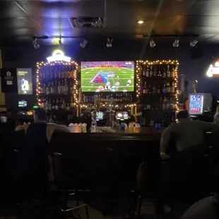 people sitting at the bar watching televisions