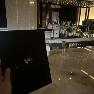 a person holding a menu in front of a bar