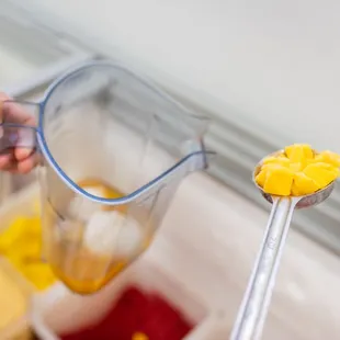 a person holding a blender and scooping it into a blender