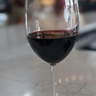 a glass of red wine on a counter