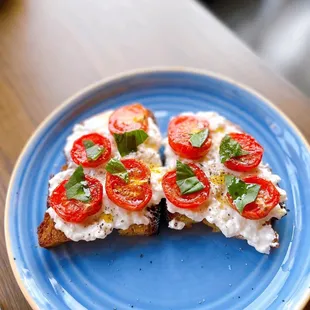 two slices of toast with tomatoes and basil