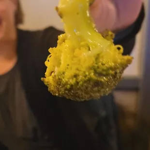 a woman holding a piece of broccoli