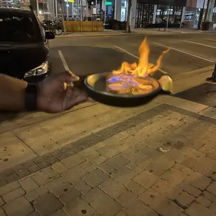 a person holding a frying pan on fire