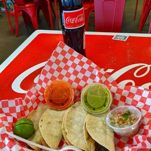 a table with a coca cola and a basket of tacos