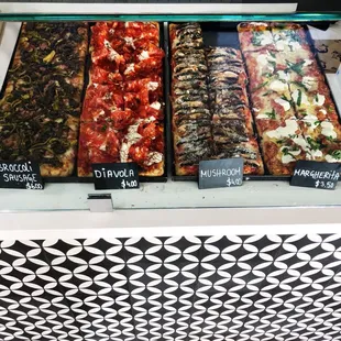 a variety of pizzas in a display case