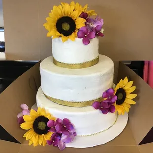 a three tiered cake with sunflowers on top