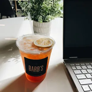 a cup of iced tea next to a laptop