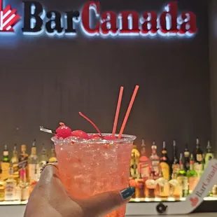 a person holding a drink in front of a bar