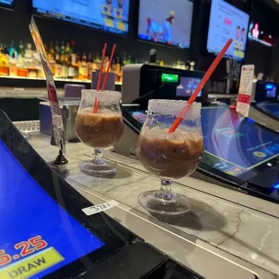 two glasses of iced coffee on a bar