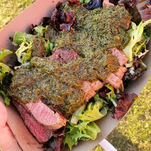 Sirloin steak with chimichurri on top of greens