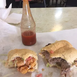 a half eaten sandwich and a bottle of ketchup