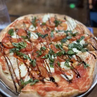a pizza with tomatoes, mozzarella, and basil