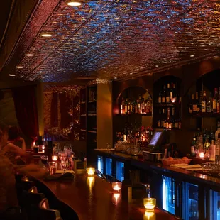 a bar with candles and people sitting at the bar