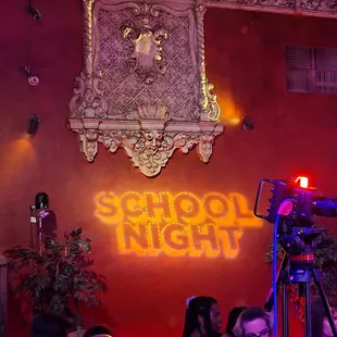 a group of people sitting in front of a neon sign