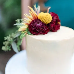 a woman holding a cake with flowers on top