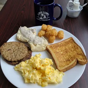 Eggs, sausage, biscuits with gravy, tatter tots and french toast with coffee.
