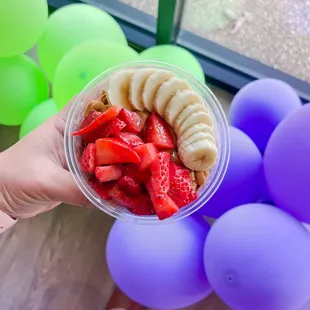 a hand holding a bowl of fruit