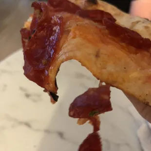 a hand holding a piece of bacon