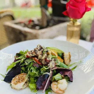 a plate of food with a rose in the background