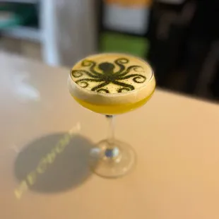 a yellow cocktail in a glass