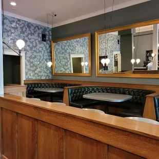the interior of a restaurant with wooden booths and mirrors