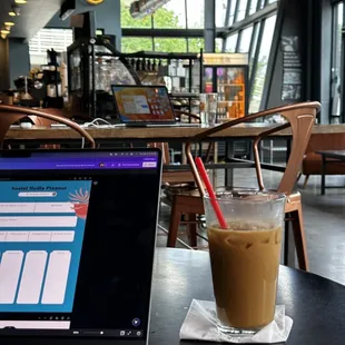 a glass of iced coffee next to a laptop