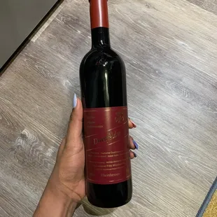 a hand holding a bottle of red wine