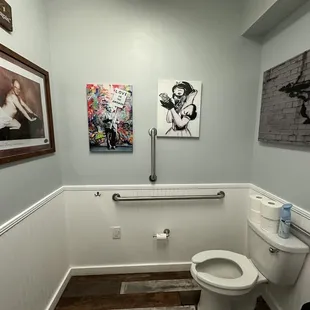 a bathroom with a toilet and a picture on the wall