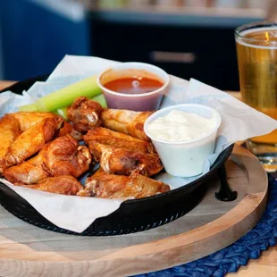 a basket of chicken wings and a glass of beer