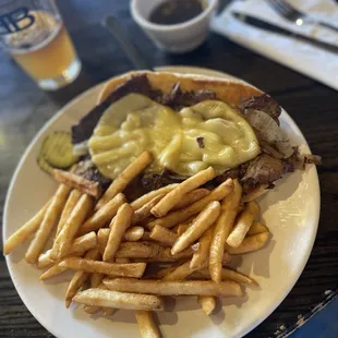 Brisket French dip with grilled onions, smoked Gouda on a grilled roll with fries and an jus.