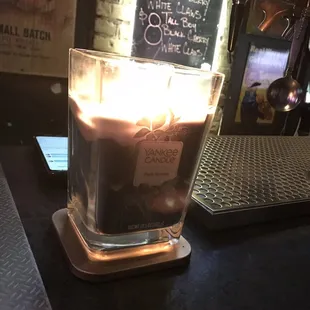 a candle lit in a glass on a bar